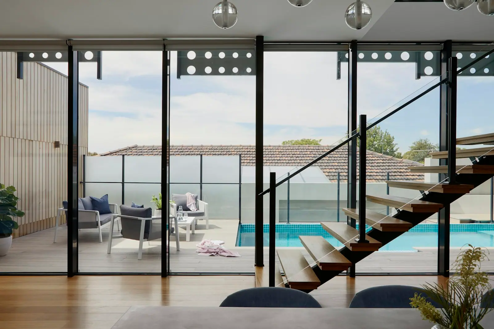 Open-plan living space with floor-to-ceiling glazing and a floating staircase